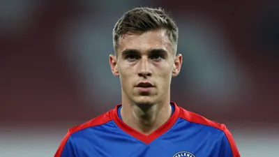 A young male footballer, mid-20s, wearing a solid blue and red Vålerenga Fotball training kit, head-and-shoulders...