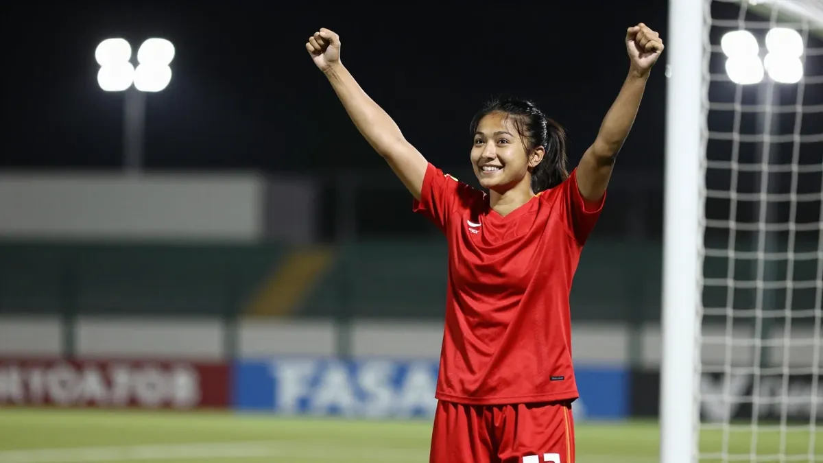 A 25-year-old female footballer in a clean red jersey and shorts, celebrating a goal with arms raised